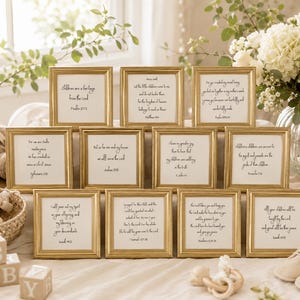 May include: A collection of eleven square gold-toned frames, each containing white paper with black printed scripture verses. The frames are arranged in a grid, featuring beaded edges and glass fronts, displaying various religious quotes.