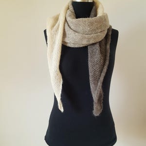Könnte beinhalten: Ein dreieckiger Schal mit einem Farbverlauf von Beige zu Braun. Der Schal ist über eine schwarze Schaufensterpuppe gelegt.