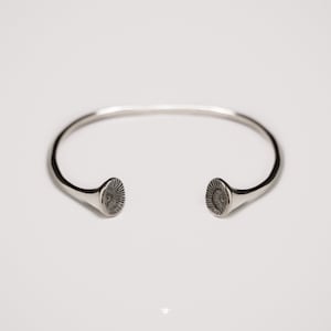 Peut inclure: Un bracelet jonc en argent avec deux extrémités circulaires texturées.