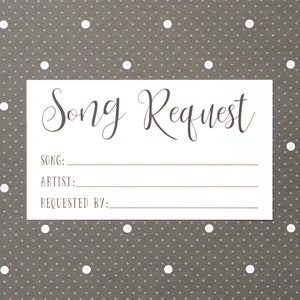 May include: A white card with the words "Song Request" in elegant script. Below the title are lines for "Song", "Artist", and "Requested By:". The card is set against a gray background with a white polka dot pattern.
