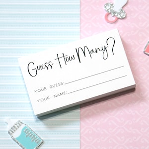 Op de afbeelding: Een stapel witte kaarten met de tekst "Guess How Many?" gedrukt in zwart script. Onder de titel staan regels voor "Your Guess:" en "Your Name:" De kaarten liggen op een achtergrond van lichtblauw en roze patroonpapier.
