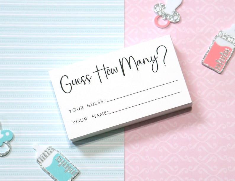 Op de afbeelding: Een stapel witte kaarten met de tekst "Guess How Many?" gedrukt in zwart script. Onder de titel staan regels voor "Your Guess:" en "Your Name:" De kaarten liggen op een achtergrond van lichtblauw en roze patroonpapier.