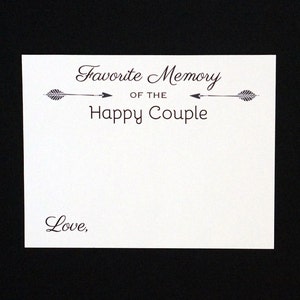 May include: A white card with the text "Favorite Memory of the Happy Couple" in a decorative font, with arrow accents. The word "Love," is written at the bottom. The card is set against a black background.