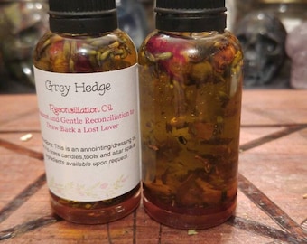 Peut inclure: Deux flacons en verre remplis d'un liquide doré et de plantes, surmontés de bouchons noirs. L'un des flacons porte une étiquette indiquant "Grey Hedge Reconciliation Oil" avec des instructions. Les flacons reposent sur une surface en bois.