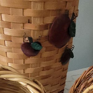 Puede incluir: Una cesta de mimbre tejida con un dise&ntilde;o de manzana marr&oacute;n y verde. La cesta est&aacute; hecha de materiales naturales y tiene un aspecto r&uacute;stico.