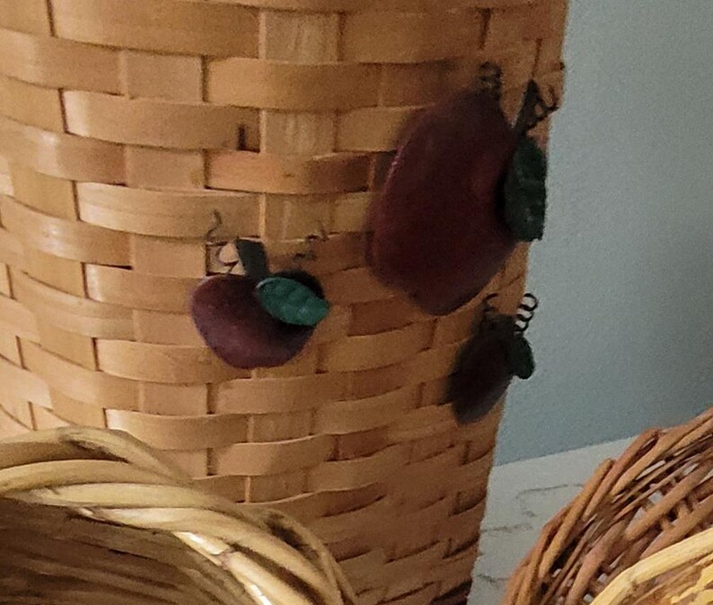 Puede incluir: Una cesta de mimbre tejida con un dise&ntilde;o de manzana marr&oacute;n y verde. La cesta est&aacute; hecha de materiales naturales y tiene un aspecto r&uacute;stico.