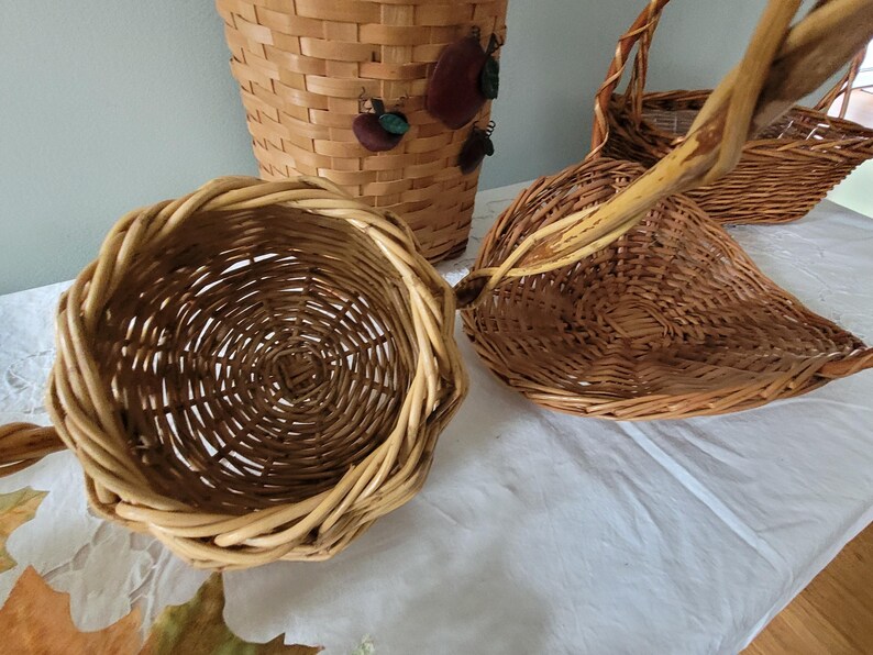Puede incluir: Cuatro cestas de mimbre tejidas en diferentes formas y tama&ntilde;os. Las cestas est&aacute;n hechas de mimbre marr&oacute;n natural y son perfectas para almacenamiento o exhibici&oacute;n.