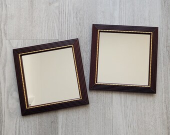 May include: Two brown picture frames with gold trim, both with blank white interiors. The frames are on a light gray wood surface.