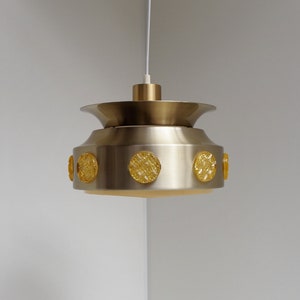 May include: A silver pendant light fixture with a circular, frosted glass shade and six yellow glass accents.