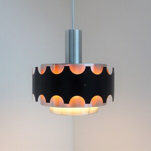 May include: A black and silver pendant light with a scalloped edge and a white cord.