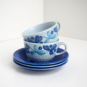 Puede incluir: Tres tazas de té azules y blancas con un patrón floral apiladas una encima de la otra. Las tazas están sobre tres platillos azules.
