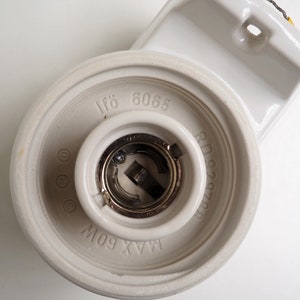 May include: White ceramic light fixture with a metal light bulb socket. The fixture has the text "If&ouml; 6065" and "MAX 60W" printed on it.