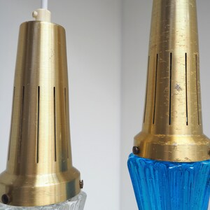 May include: Two gold pendant lights with blue and clear glass shades. The shades have a textured, rippled design.