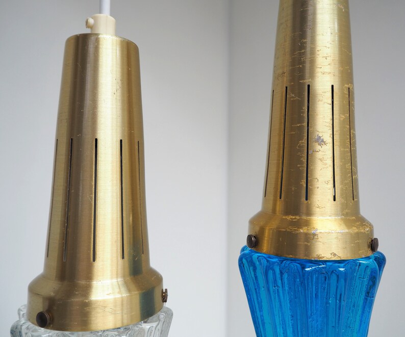 May include: Two gold pendant lights with blue and clear glass shades. The shades have a textured, rippled design.