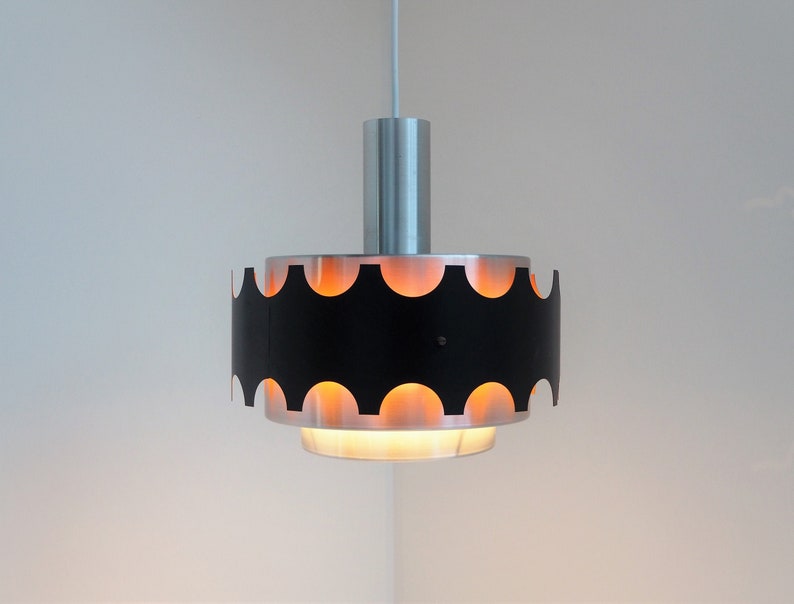 May include: A black and silver pendant light with a scalloped edge and a white cord.