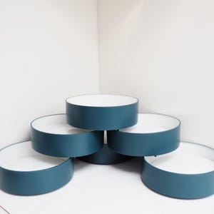 May include: Six teal-coloured, round, open-top containers with white interiors are stacked in a pyramid shape. The containers are evenly spaced and arranged against a white background.