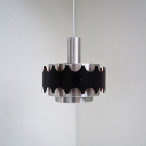 May include: A silver and black pendant light with a scalloped edge. The light is hanging from a white cord.