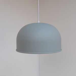 May include: A light gray dome-shaped pendant light fixture hangs from a white cord against a white wall.