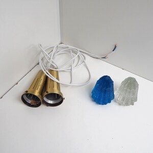 May include: Two brass light fixtures with white cords and two glass lampshades, one blue and one clear.