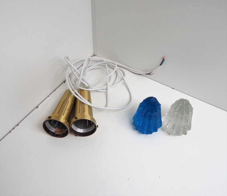 May include: Two brass light fixtures with white cords and two glass lampshades, one blue and one clear.