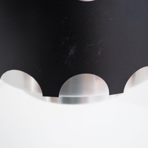 May include: Black pendant light fixture with a scalloped edge and a silver interior.