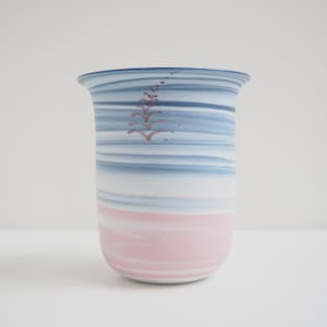 Könnte beinhalten: Eine Keramikvase mit einem blauen und rosa Wirbelmuster. Die Vase hat eine breite Öffnung und einen schmalen Boden.