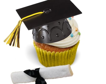 May include: A cupcake with white frosting and colorful sprinkles, topped with a black graduation cap with a yellow tassel. A rolled-up diploma tied with a black ribbon rests below the cupcake. The cupcake sits in a yellow paper liner.