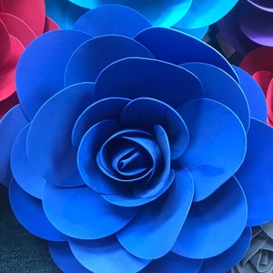 May include: A large, blue paper flower with multiple layers of petals. The flower is made of paper and has a realistic appearance.