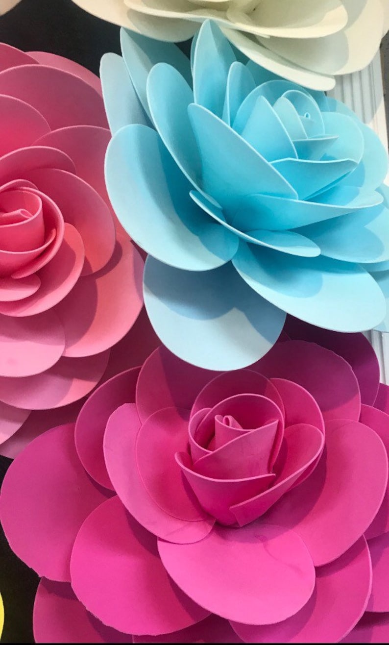 May include: Three large paper flowers in pink, blue, and hot pink. The flowers are made of multiple layers of paper, creating a 3D effect.