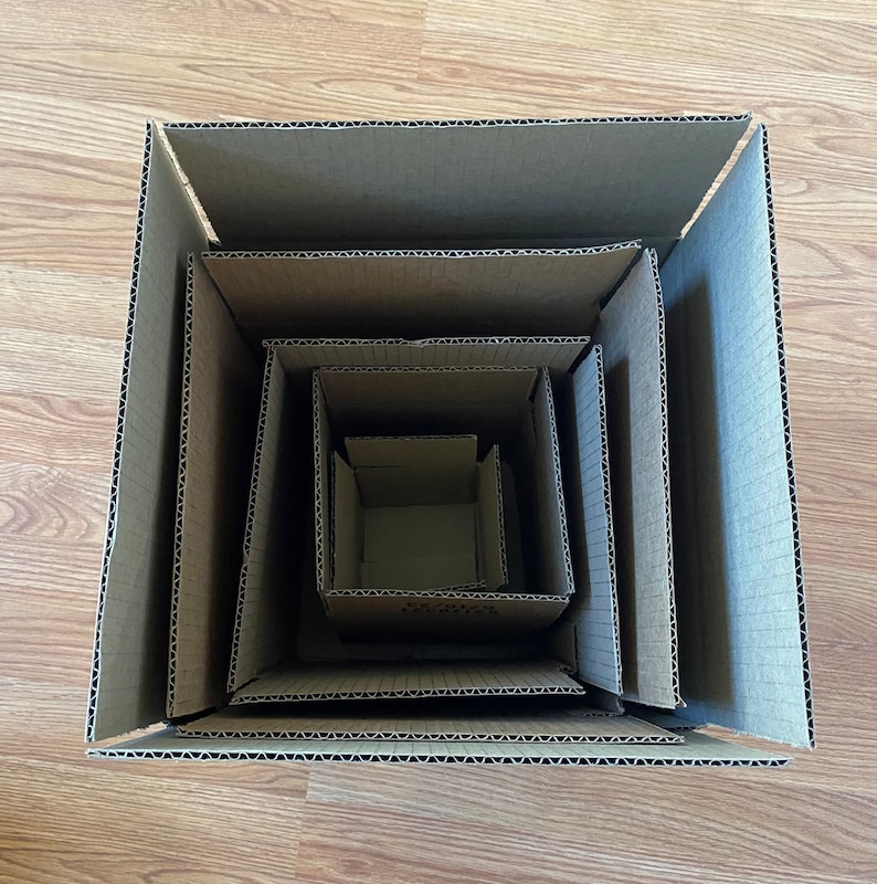 May include: A set of five nested cardboard boxes, each slightly smaller than the one before it. The boxes are all made of brown cardboard and have a corrugated texture.