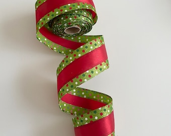 Puede incluir: Un rollo de cinta decorativa con un diseño festivo. La cinta presenta secciones alternas de rojo liso y verde con lunares blancos y rojos. La cinta está hecha de un material brillante y es ideal para manualidades y envolver regalos.