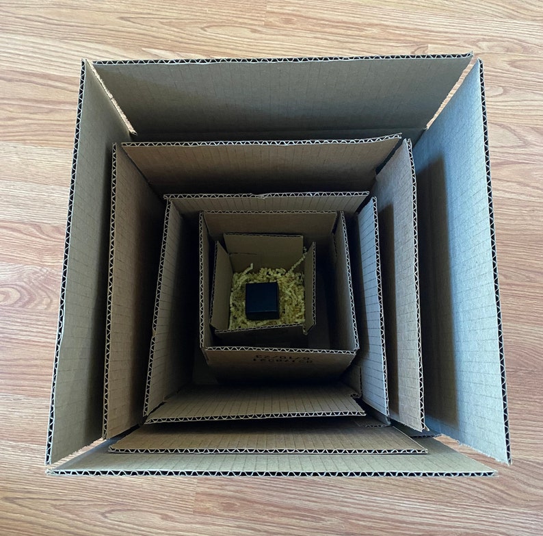 May include: A brown cardboard box with multiple layers, each layer slightly smaller than the one before it. The box is empty, but the layers are visible, creating a nested effect.