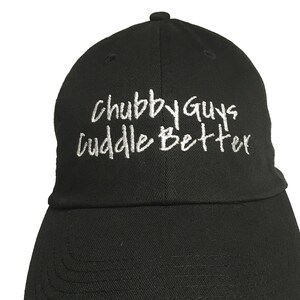 May include: Black baseball cap with white embroidered text that reads "Chubby Guys Cuddle Better".