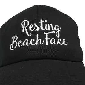 May include: Black baseball cap with white embroidered text that reads "Resting Beach Face".