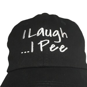 May include: A black baseball cap with white embroidered text that reads "I Laugh... I Pee"