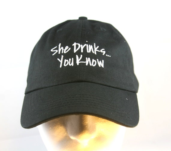 She Drinks... You Know- Polo Style Ball Cap (Black with White Stitching)