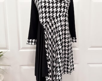 May include: Black and white houndstooth print dress with a black asymmetrical hem and a large black flower accent on the shoulder.
