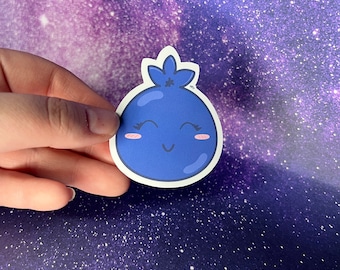 May include: A die-cut sticker of a smiling cartoon blueberry. The blueberry is a vibrant blue with a white outline, pink cheeks, and a green stem. The sticker is held against a purple and white galaxy background.