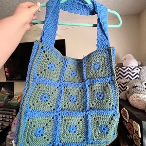 May include: A crocheted tote bag with blue and green squares. The bag has a blue crocheted strap.