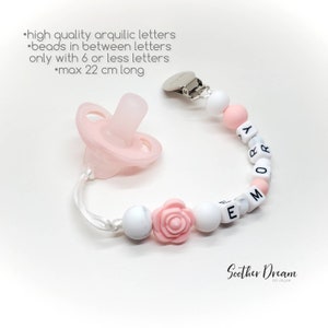 Peut inclure: Une sucette en silicone rose clair attach&eacute;e &agrave; une attache-sucette perl&eacute;e avec des perles rondes blanches et roses, une perle en forme de rose rose et des perles cubiques blanches avec des lettres noires formant le pr&eacute;nom EMORY.