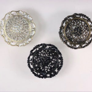 Peut inclure: Trois plaques métalliques décoratives avec des motifs de filigrane complexes. Les plaques sont en noir, blanc et or.