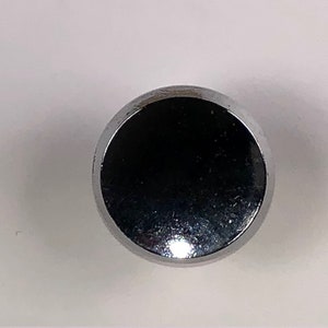 May include: A round, silver-coloured knob with a smooth, shiny surface.