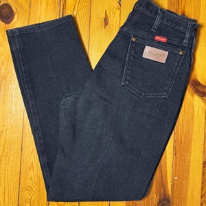 May include: A pair of dark blue denim jeans with a Wrangler label on the back pocket.