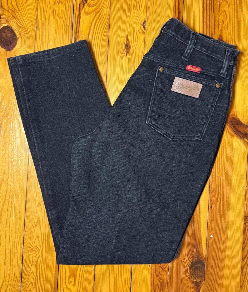 May include: A pair of dark blue denim jeans with a Wrangler label on the back pocket.