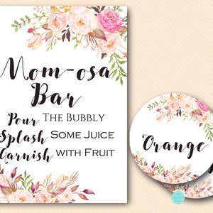 Op de afbeelding: Een printbaar bord voor een "Mimosabar" met bloemendecoraties. Het bord geeft gasten de instructie om "de bubbels in te schenken, wat sap toe te voegen en te garneren met fruit". Twee ronde labels met bloemendecoraties zijn ook inbegrepen, een met het woord "Orange" erop.