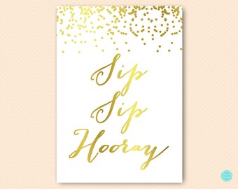 May include: A white sign with gold confetti at the top and the words "Sip Sip Hooray" written in gold cursive.
