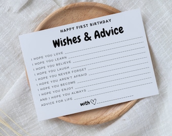May include: A printable card with the text "Happy First Birthday Wishes & Advice" and a list of phrases like "I hope you love", "I hope you learn", "I hope you believe", and "I hope you laugh". The card is on a light brown wooden surface.
