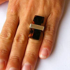 May include: A silver ring with a rectangular brown stone set in the centre. The stone has a marbled pattern.