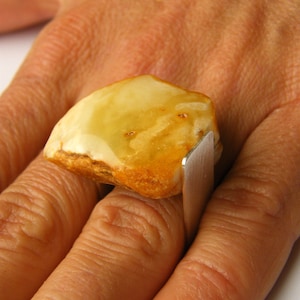 May include: A ring with a large, amber-colored stone set in a silver band.