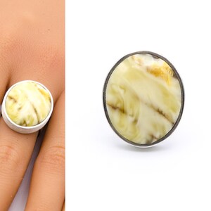 May include: A silver ring with a round, yellow and white agate stone.